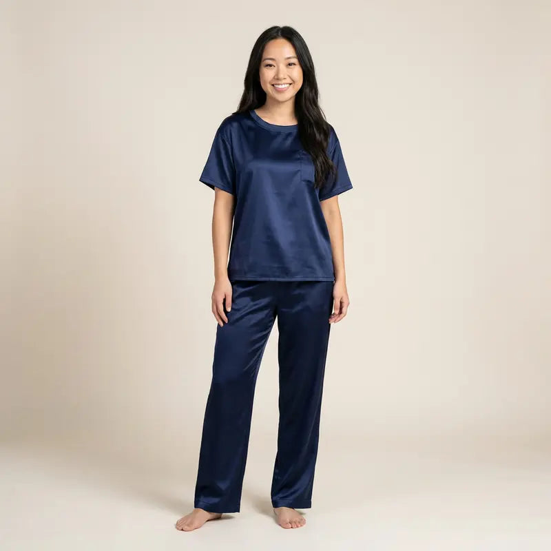 Femme portant un pyjama en satin bleu marine, composé d’un t-shirt à manches courtes et d’un pantalon long, debout face à la caméra sur fond neutre.