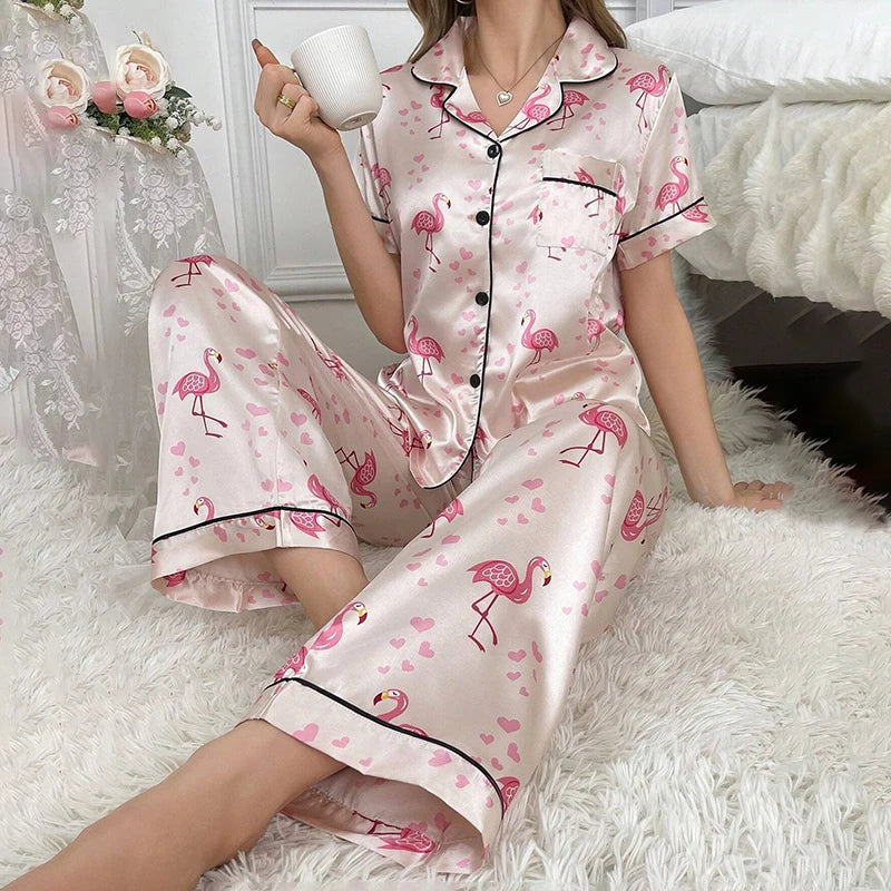 Pyjama satin rose imprimé flamants roses porté par une femme assise sur un tapis blanc